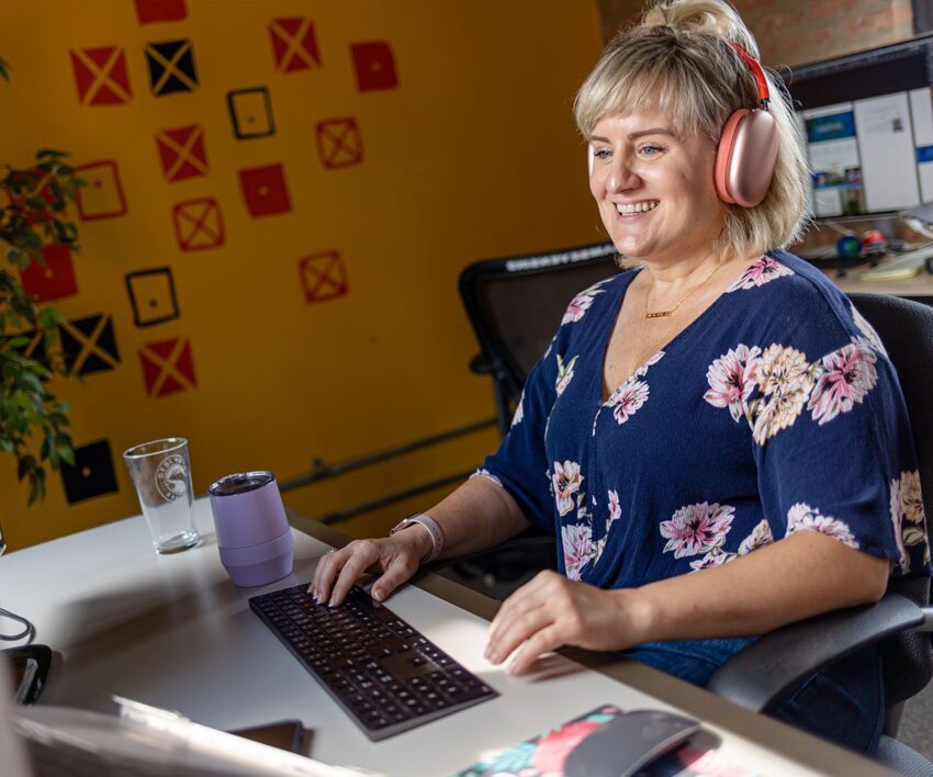 Orbiteer, Shellie, smiling and working at her desk