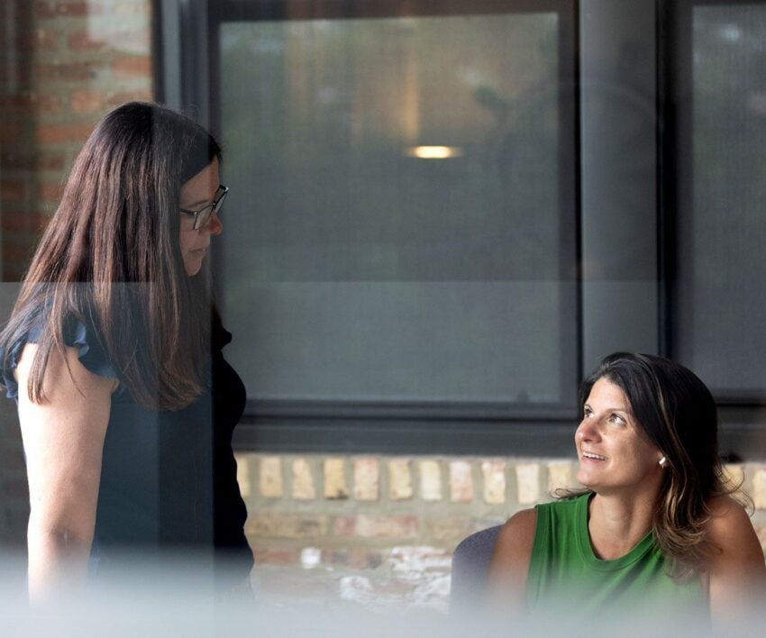 Orbiteers, Stephanie and Mari seen through a window having a discusson