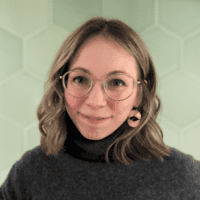 A woman wearing glasses and a turtle neck sweater.
