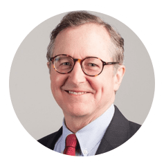 A smiling man with glasses, wearing a suit and tie.