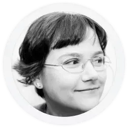 Black and white headshot of a person with short hair, glasses, and earrings, looking to the right and smiling slightly.
