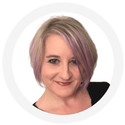 Woman with short, light purple and blonde hair, wearing a black top, smiling, shown against a white background in a circular frame.